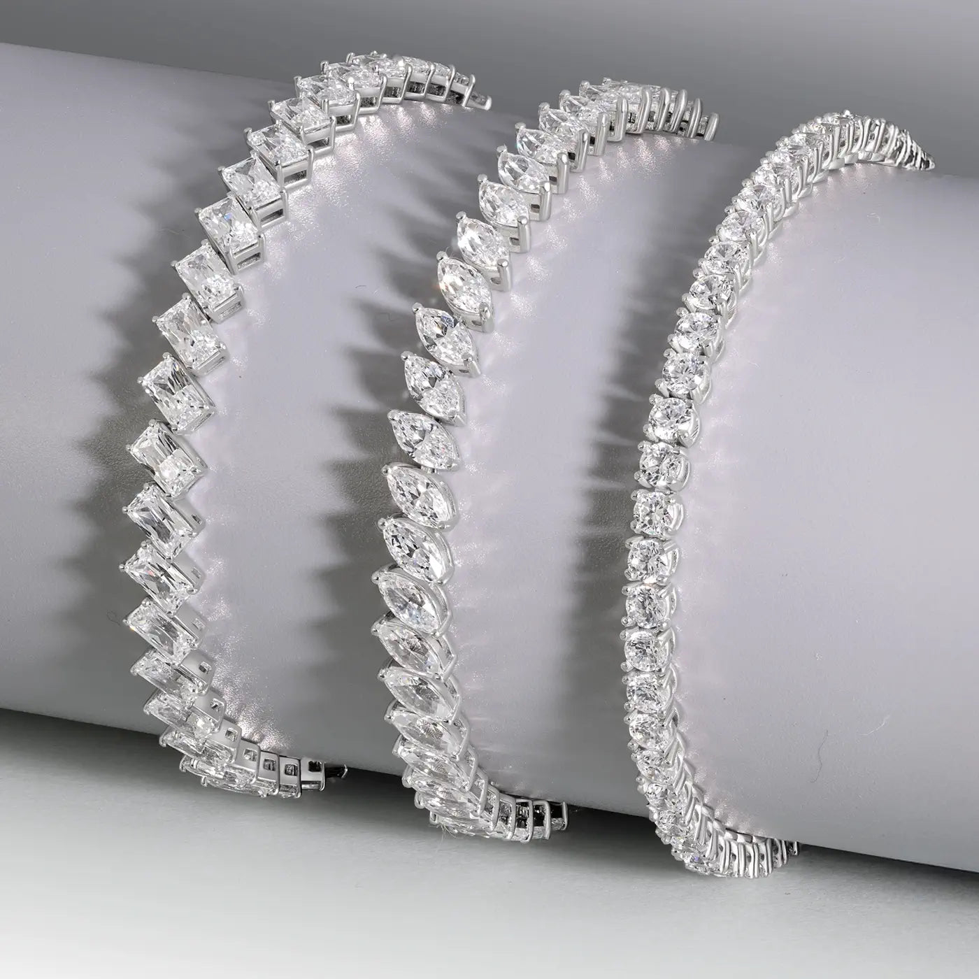 Three diamond and 18k white gold bracelets on a gray surface