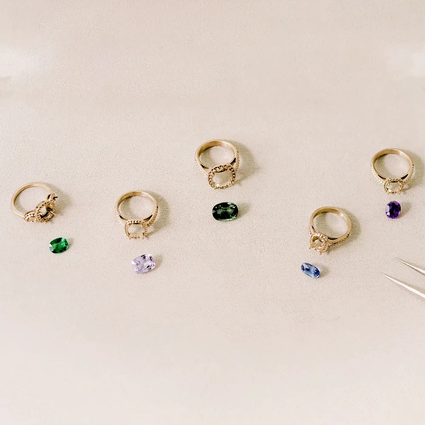 Bagues en or 18 carats serties de pierres précieuses colorées sur fond beige clair