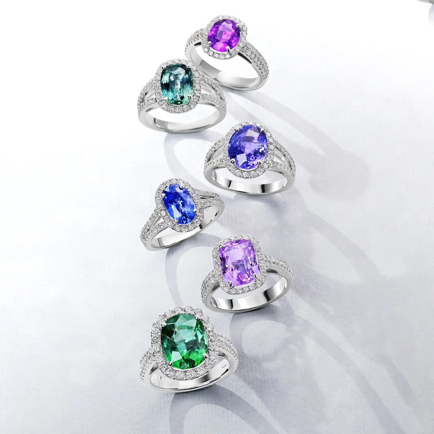 Set of six 18k whit gold rings with color gemstones on a white background