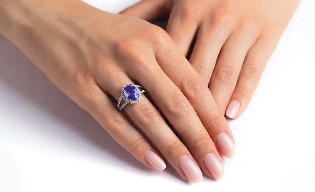 Hand wearing a Blue Sapphire & Diamonds ring on a white background