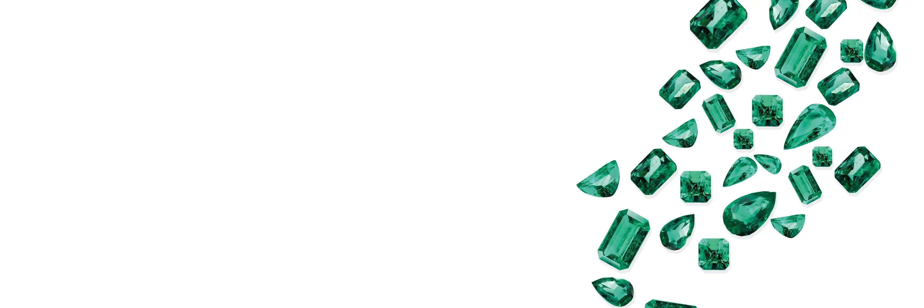 Emerald gemstones arranged in a scattered pattern on a white background