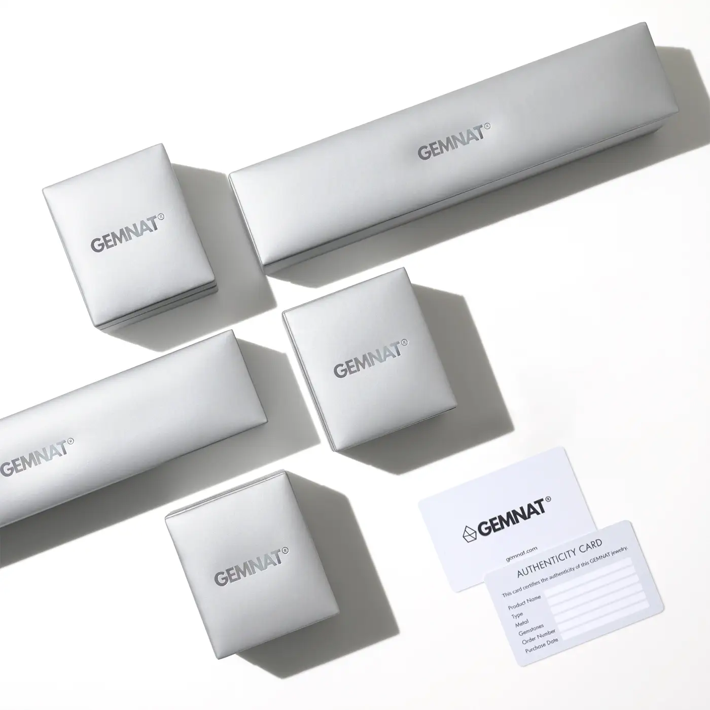 GEMNAT jewelry packaging including boxes and an authenticity card on a white background