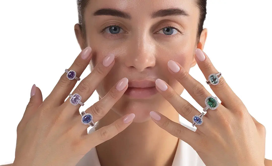 Woman wearing multiple rings with natural gemstones on a white background